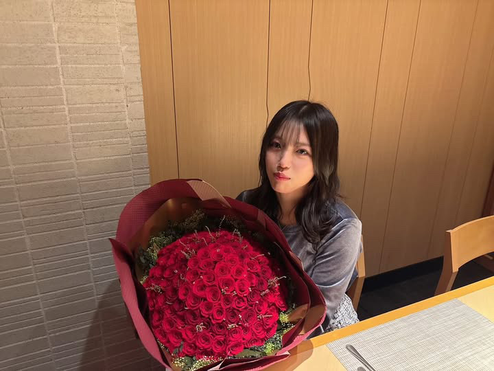 108本の赤バラを受け取り笑顔の女性